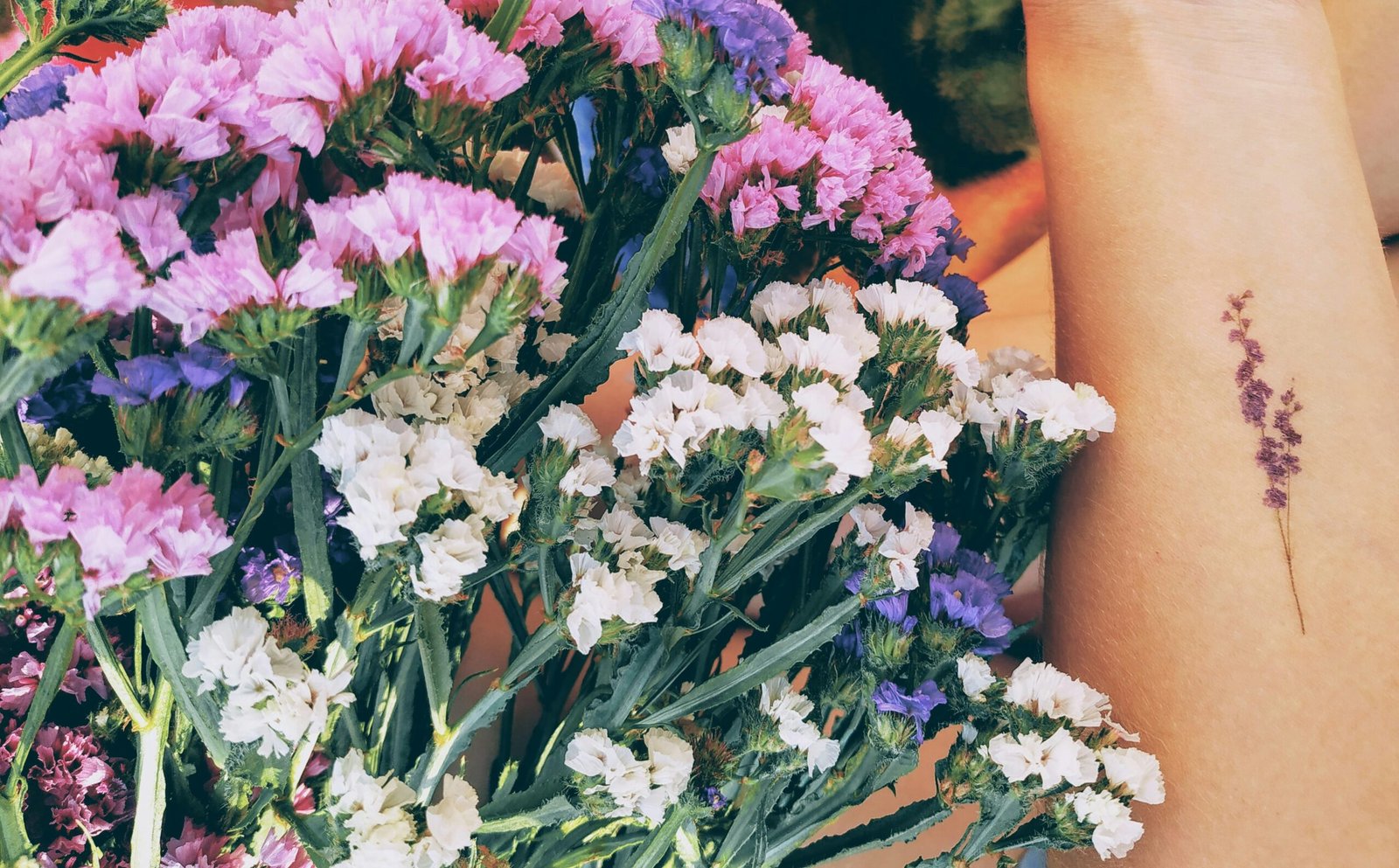 a bunch of flowers and a tattooed hand