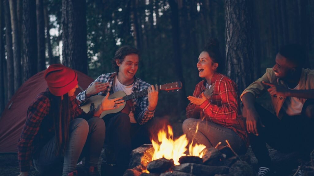 four friends enjoying music sitting around a campfire